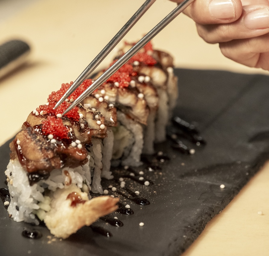 Hands with raw tuna to make sushi